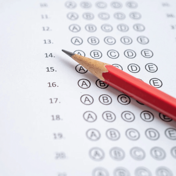 Photo shows a multiple-choice answer sheet with a red pen on top of it.
